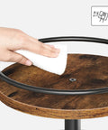 Hand cleaning rustic brown tier of 3-Tier Lazy Susan Organizer With Rotating Turntable Spice Rack, dark metal border visible.