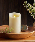 Cozy Ivory Flameless LED Pillar Candle With Moving Flame on wooden tray with flowers, 3.5 by 5 inch, in home decor setting