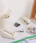 Beige must-have all in one desk organizer set with stapler, tape dispenser, scissors, and clips on desk.