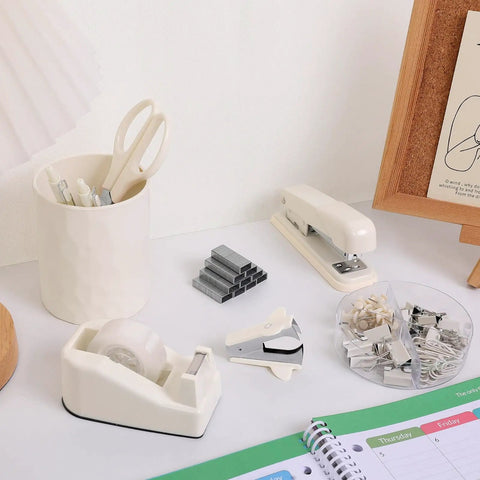 Beige must-have all in one desk organizer set with stapler, tape dispenser, scissors, and clips on desk.