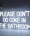 White LED sign with text 'PLEASE DON'T DO COKE IN THE BATHROOM', clear acrylic backboard and visible wall screws.