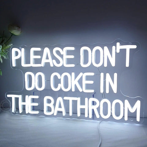 White LED sign with text 'PLEASE DON'T DO COKE IN THE BATHROOM', clear acrylic backboard and visible wall screws.