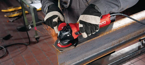 Professional Grade 1300W 230V Angle Grinder Featuring 125MM Disc Size cutting metal with sparks in workshop, held by gloved hand.