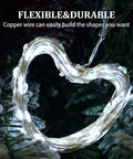 Two Pack Solar String Lights With 100 LEDs On 33 Foot Copper Wire forming a heart shape, wrapped around greenery, glowing.