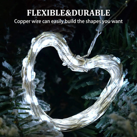Two Pack Solar String Lights With 100 LEDs On 33 Foot Copper Wire forming a heart shape, wrapped around greenery, glowing.