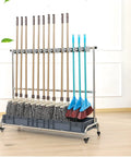 Stainless Steel Broom And Mop Holder With Movable Cart Organizer For Cleaning Tools, Slim Rack For Brooms And Mops, Dustpan, Shovels And Vacuum, Drip Tray Included, Ideal For Garages, Hotels, Schools And Offices displayed with tools.