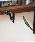 Heavy Duty Iron Triangle Shelf Brackets Black Metal Corner Supports 4 Pack mounted on wood shelf with plant nearby.