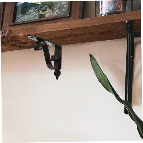 Heavy Duty Iron Triangle Shelf Brackets Black Metal Corner Supports 4 Pack mounted on wood shelf with plant nearby.
