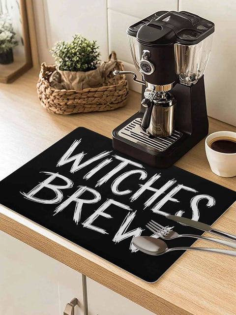 Spooktacular Black Witches Brew Coffee Station Mat Featuring Quick Dry Absorbent PU Material Designed For Kitchen Counter Espresso Machine Setup 28 By 18 Inch Halloween Spill Proof Drip Catch Pad on kitchen counter with espresso machine.