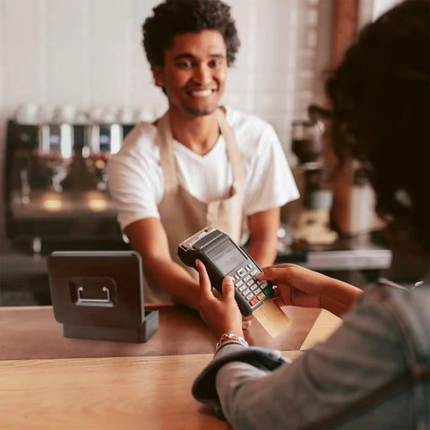 Cashier smiling with a payment terminal in hand, Sturdy Locking Cash Box With Pull Out Tray And Five Compartment Organizer on counter.