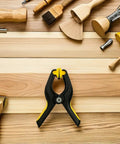One black clamp from Eight Pack LCD Screen Fastening Clamps With Scratch Free Sponge Pads for repairs, among various tools on wooden surface.