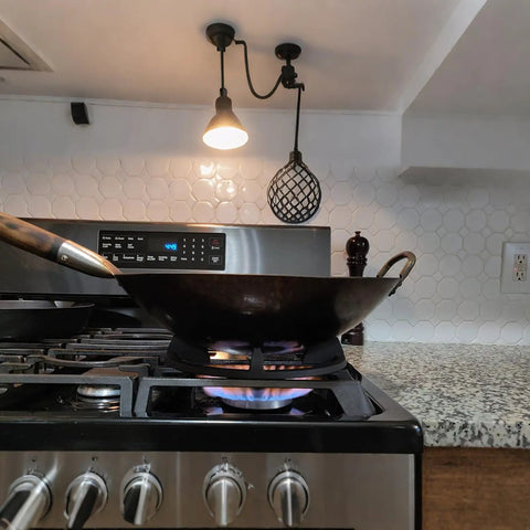 A round-bottom wok on a gas stove using a Cast Iron Wok Ring Support For Gas Stoves 9.37 Inch Outer Diameter Stable Base.