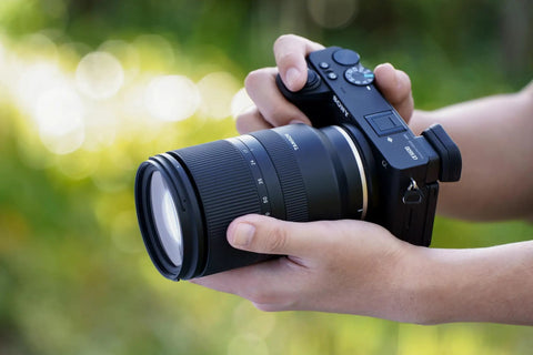 Person holding camera with 17-70mm F2.8 Di III A VC RXD Lens For Sony E APS-C Mirrorless Cameras, outdoors