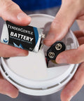 Inserting a 9V TenderGentle alkaline battery into a smoke detector for reliable power in emergency use.