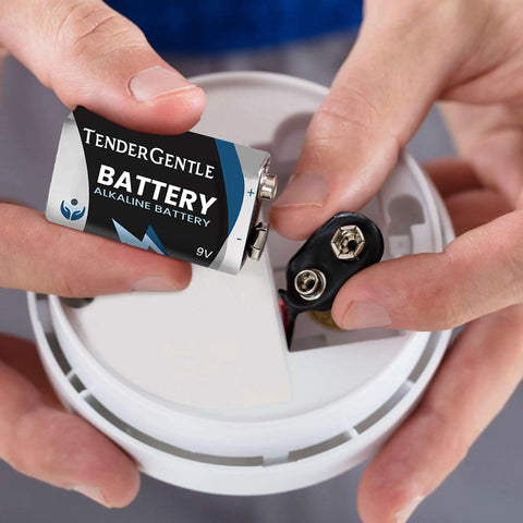 Inserting a 9V TenderGentle alkaline battery into a smoke detector for reliable power in emergency use.