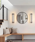 ElilyGiA 16 Inch Modern LED Wall Sconce Vanity Light, Black mounted beside a round mirror in a stylish entryway.