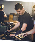 Men wearing Built Tough Cut Resistant Wrist Sleeves for Mechanics and Yard Crews, working on automotive tasks in a workshop.