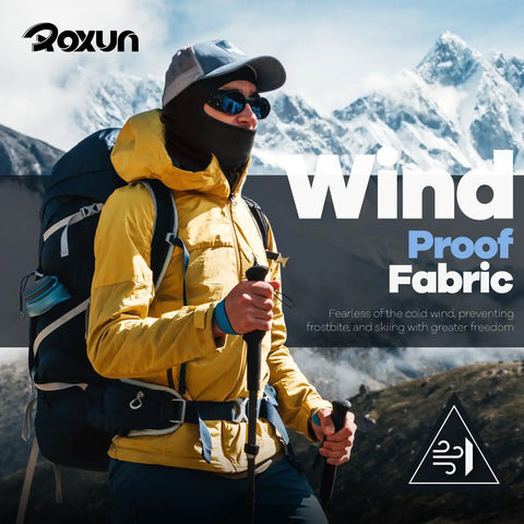 Hiker wearing yellow jacket and dark Balaclava Ski Mask 5 Pack Neck Gaiter for Motorcycle and Outdoor Sports All Season Face Covering with UV Protection Cooling Breathable Fabric Windproof Dust Proof Sand Guard Reusable and Machine Washable, snowy mountains in background.