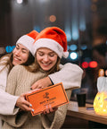 Two women in Santa hats embrace beside Sister Birthday Gift From Sister Best Friend Gift For Women Candle Holder With Flickering LED Flameless Candle.