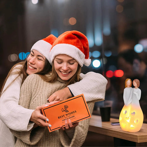 Two women in Santa hats embrace beside Sister Birthday Gift From Sister Best Friend Gift For Women Candle Holder With Flickering LED Flameless Candle.