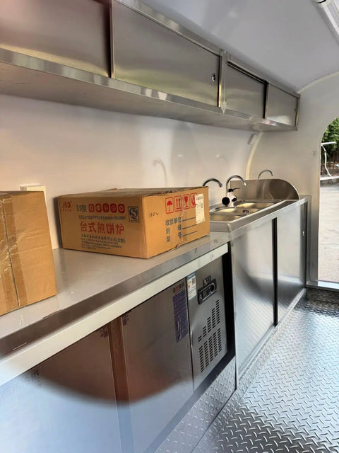 Interior of custom mobile coffee and pastry trailer showcasing a sink, fridge, and stainless steel counters for street vending.