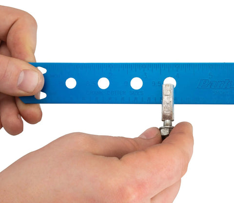 Hands using Spoke Bearing And Cotter Gauge For Bicycles, Handy Wheel Maintenance Tool to measure cotter pin size with blue scale.