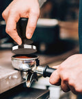 Hand using 51mm Calibrated Espresso Tamper With Spring Loaded Mechanism, Weighted Hand Tamper For Home Baristas, Fits Delonghi EC Series Breville Gaggia And More, Precision 51mm Portafilter Tamping For Consistent Shots on portafilter.