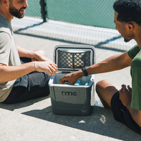 Two men using Road Trip 8 Qt Personal Cooler Compact And Lightweight Insulated Ice Chest That Fits Up To 12 Cans, open with drinks.