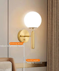 Gold Glass Globe Wall Sconce Light With Mid Century Vibe Indoor Wall Mounted Lamp in bedroom, dimmer and on/off switches visible.