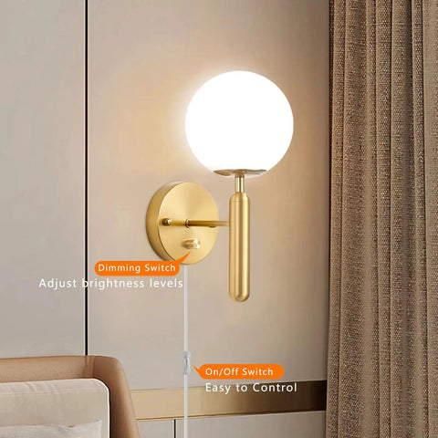 Gold Glass Globe Wall Sconce Light With Mid Century Vibe Indoor Wall Mounted Lamp in bedroom, dimmer and on/off switches visible.