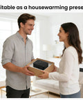 Man and woman exchanging a gift box in a living room, suitable as a housewarming present, with a small appliance inside.