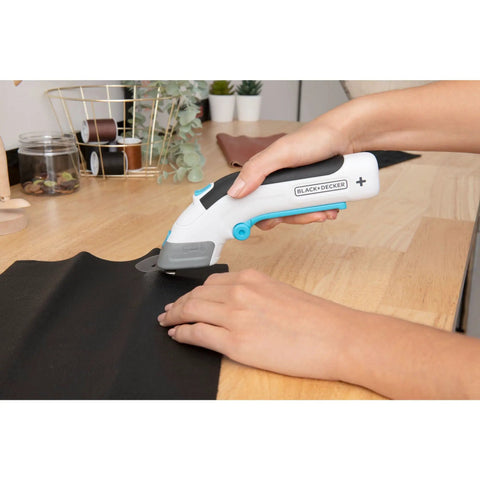 Black And Decker 4V Max Cordless Electric Fabric Craft Scissors With Usb Rechargeable Battery cutting black leather on wood surface.