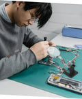 Person using Pro Grade Repair Clip Magnifying Mirror and PCB Holder for Soldering Station, electronics repair setup.