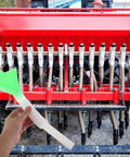 Hand holding Seed Planter Tube Replacement Part Plastic Seed Distribution Tube For Corn in front of farming machinery