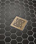 4 Inch Square Shower Floor Drain Champagne Gold Tile In Kit installed in hexagon patterned black tile floor.