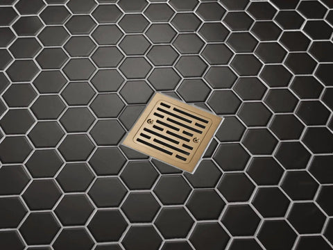 4 Inch Square Shower Floor Drain Champagne Gold Tile In Kit installed in hexagon patterned black tile floor.