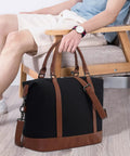 Man seated holding Canvas Travel Tote Bag For Women With Zipper, Weekender Duffel And Carry On Tote, black with brown straps