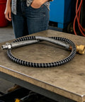 Heavy Duty Air Hose For Compressor Rock Solid Brass Lock Joints Hella Flexible Anti Kink Tubing on workbench with brass fitting.