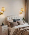 PENACINY Battery Operated Rattan Wall Sconces Set of 2 placed beside a bed with pillows and a cozy blanket in a stylish bedroom.