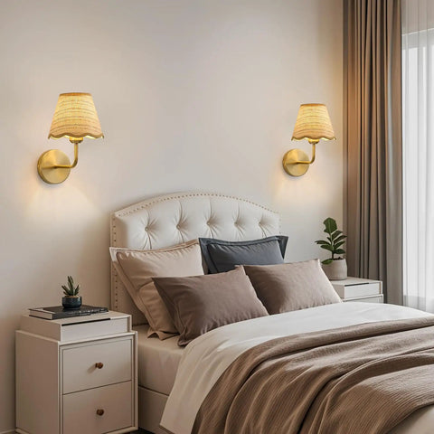 PENACINY Battery Operated Rattan Wall Sconces Set of 2 placed beside a bed with pillows and a cozy blanket in a stylish bedroom.