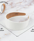 Slay Your Daily Hair Game With This Super Comfy Two Inch White Vegan Leather Headband For Women Featuring Nonslip Inner Lining To Stay Secure During Gym Workouts Or Lazy Sundays And Weekends shown on marble background with dimensions 5in wide and 6in long.