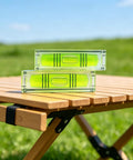 2 Pack Magnetic Mini Bubble Level Tool 2 Inch, Small Pocket on wooden table outdoors with green grass background.