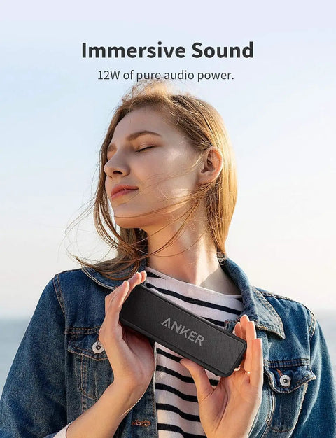 Woman holding Beefy Bass Portable Bluetooth Speaker With Crisp Stereo Sound, IPX7 Waterproof, enjoying music outdoors.