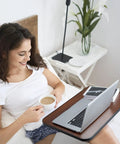 Woman enjoying coffee while using Smooth Rollin Mobile Adjustable Height Portable Computer Desk With Lockable Casters For Top Tier Home Office Standing Laptop Workstation Dark Wood Finish in bed.