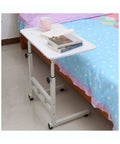 Adjustable Height Rolling Overbed Table With Easy Glide Casters For Bed Sofa Or Recliner Solid Sturdy Laptop Desk beside a bed.