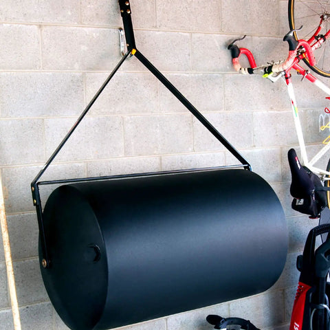 Tow Behind Lawn Roller 690 Lb Capacity With Easy Turn Plug, 36 Inch Wide Poly Drum in flat black finish stored in a garage