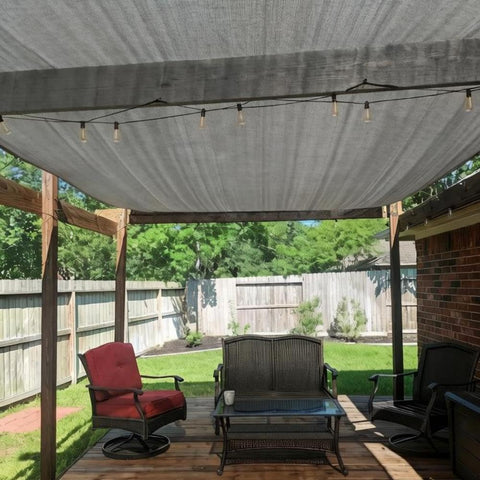 Outdoor patio with 90 Percent UV Blocking Sun Shade Cloth 10x15 Feet With D Rings For Pergola, providing shade over furniture.