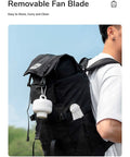 Man carrying backpack with Portable Camping Fan With 8000mAh Battery attached, showing detachable blades and hanging hook.