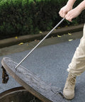 Heavy Duty Stainless Steel Manhole Cover Hook With Chunky Thick Handle Rock Solid T Shaped Grip For Pro Contractors And Builders Designed To Haul Heavy Loads Without Breaking A Sweat, lifting a manhole cover.