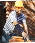 Slip On These Hella Tough Cut Resistant Arm Sleeves For Reliable Lightweight Wrist Guard Protection Built For Mechanic Jobs Welding And Outdoor Projects worn by a man building with bricks outdoors.
